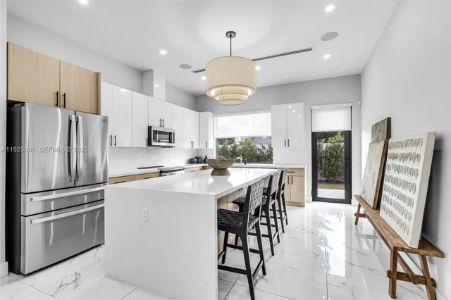 a kitchen with stainless steel appliances a refrigerator a stove a sink a dining table and chairs with wooden floor