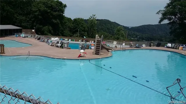 a view of a swimming pool with lawn chairs under an umbrella