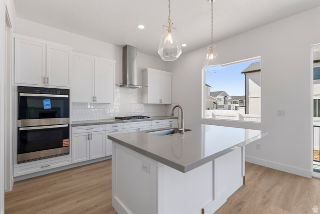 58 South Crimson Way, Unit 306 Mapleton, UT 84664 - Photo 10 of 24 Bright kitchen featuring white cabinetry, light-toned countertops, stainless steel double ovens, a matching range hood, and wood-finish flooring