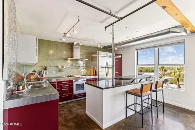a kitchen with kitchen island a stove a sink a dining table and chairs