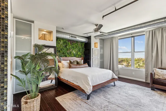 a bedroom with a bed table flowerpot and a window