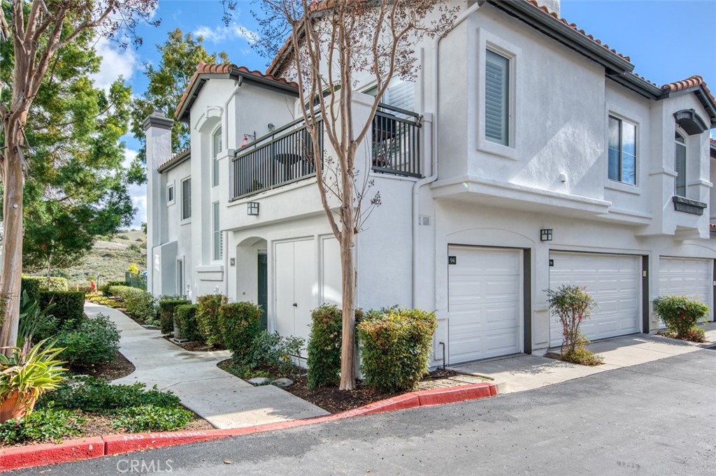 a view of a white house with large windows and plants