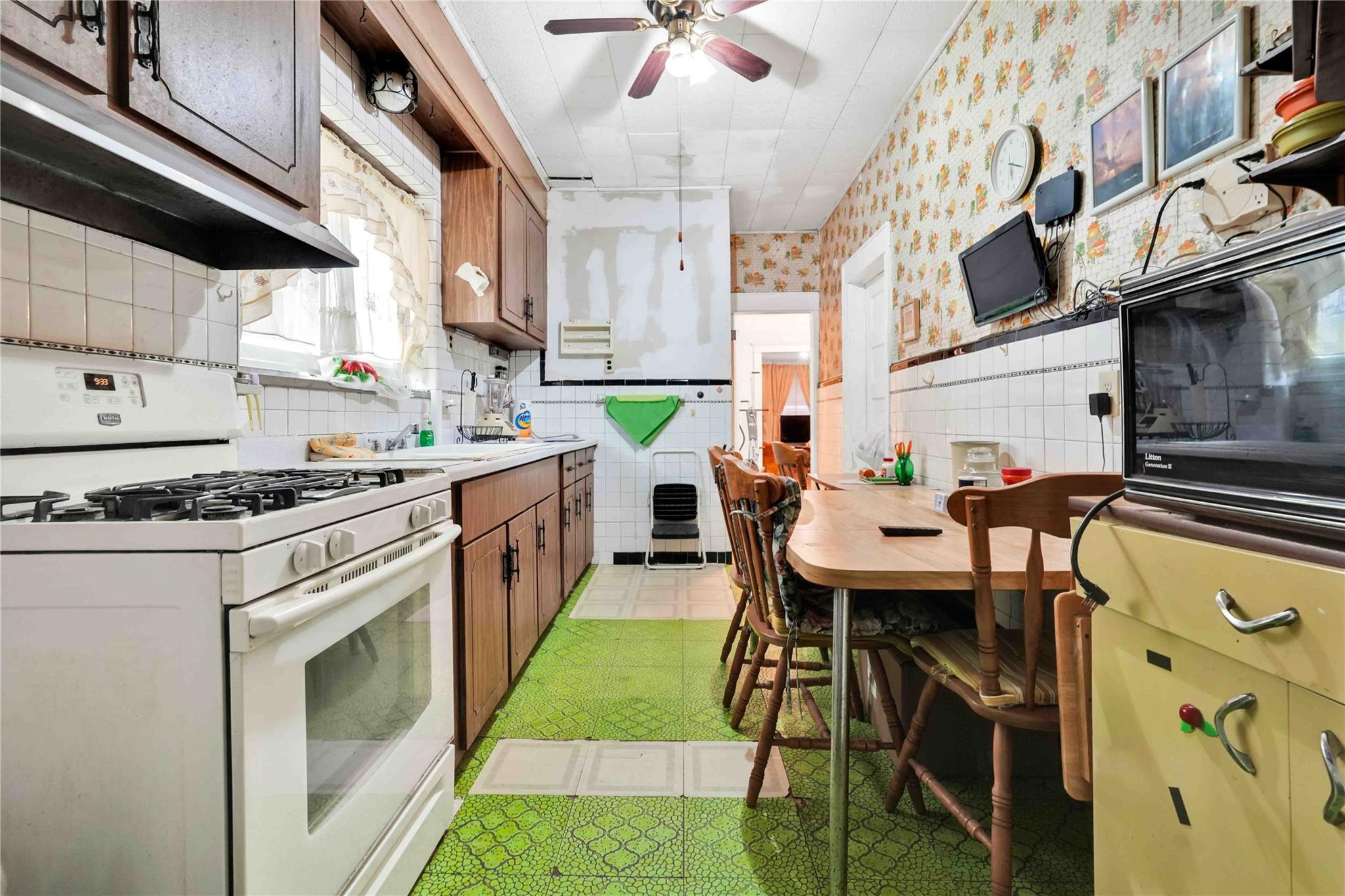 9908 35th Avenue Queens, NY 11368 - Photo 8 of 22 a kitchen with a stove a sink and a refrigerator