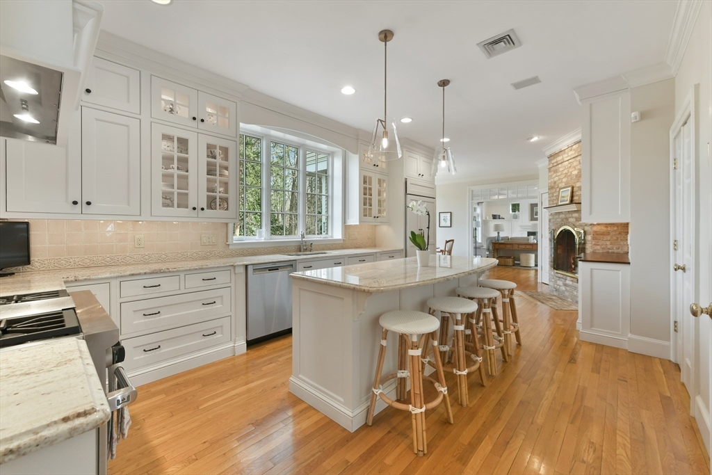 11 Olmsted Drive Hingham, MA 02043 - Photo 9 of 36 a kitchen with stainless steel appliances kitchen island granite countertop a table chairs refrigerator and sink