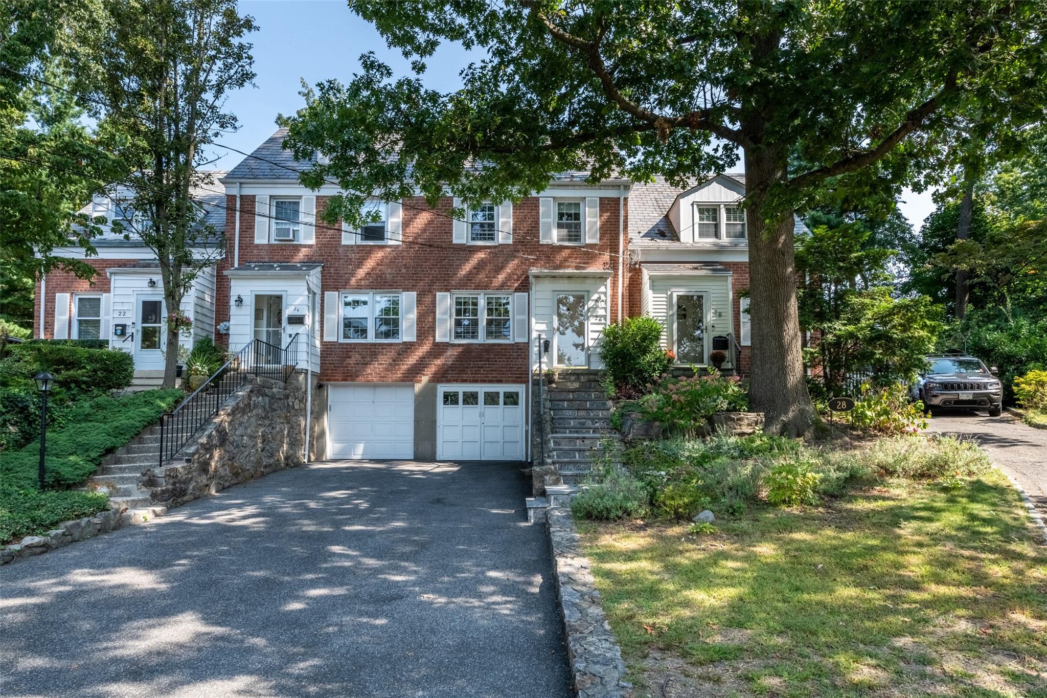 26 Elkan Road Larchmont, NY 10538 - Photo 1 of 1 View of front of house featuring stairway, an attached garage, brick siding, and aphalt driveway