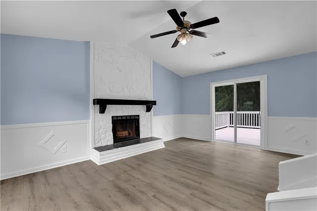 a view of an empty room with wooden floor fireplace and a window