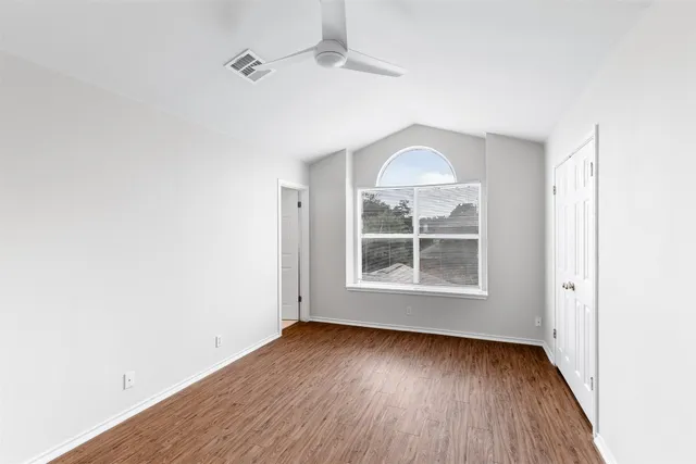 an empty room with wooden floor exposed radiator and windows
