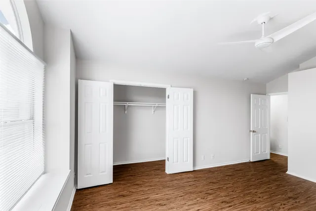 a view of an empty room with wooden floor and closet
