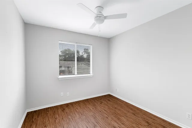 an empty room with a window and wooden floor