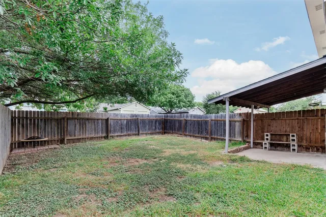 a view of a backyard with a chair and potted plants