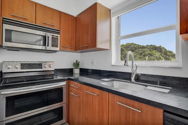 a kitchen with stainless steel appliances granite countertop a microwave a stove and white cabinets