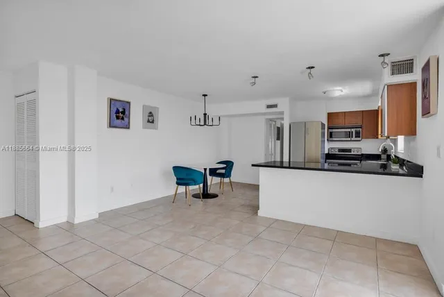 a kitchen with stainless steel appliances kitchen island granite countertop a refrigerator a stove a sink dishwasher and white cabinets with wooden floor