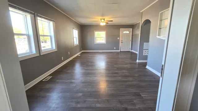 a view of an empty room with wooden floor and a window