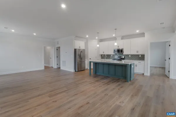 a view of kitchen with kitchen island wooden floor center island and stainless steel appliances