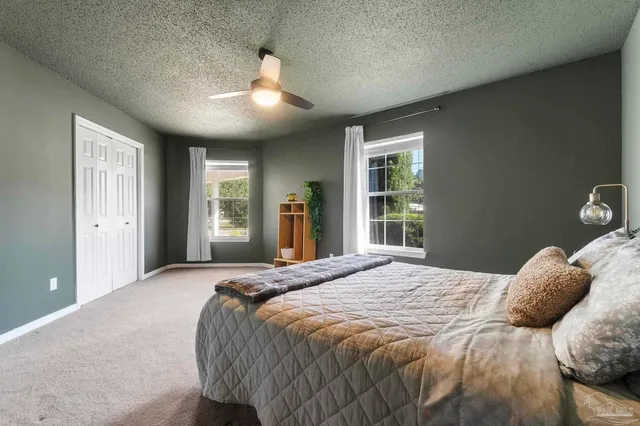 a spacious bedroom with a bed and a ceiling fan