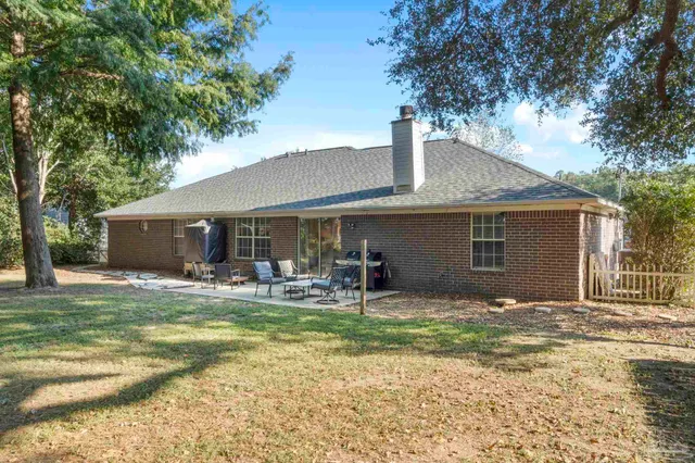 a backyard of a house with large trees and a wooden bench