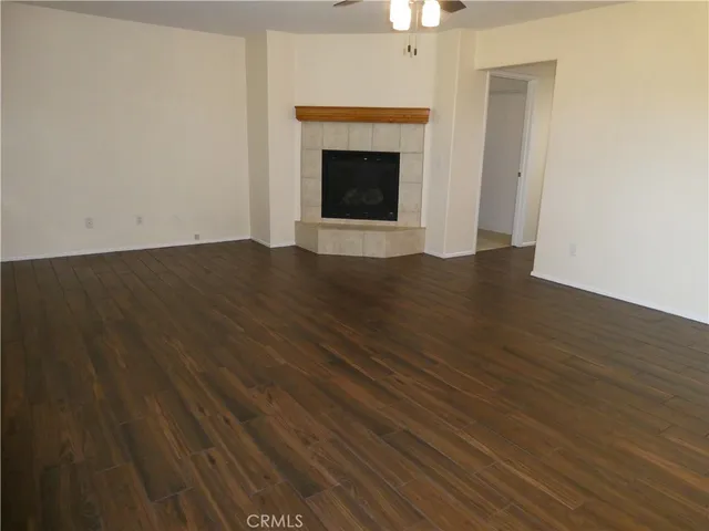 a view of an empty room with wooden floor fireplace and a window