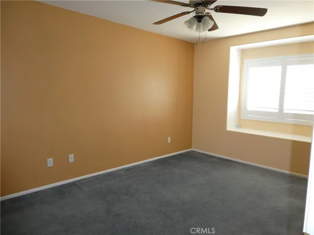 an empty room with a window and a ceiling fan