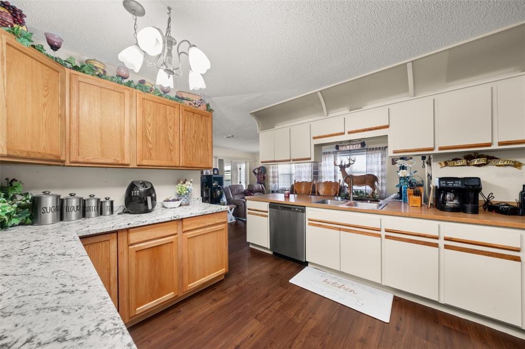 443 Foxdale Road Lake Placid, FL 33852 - Photo 12 of 31 a kitchen with stainless steel appliances granite countertop a sink dishwasher stove and white cabinets with wooden floor