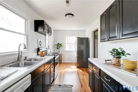 a kitchen with stainless steel appliances a sink dishwasher a refrigerator a stove and a sink with wooden floor