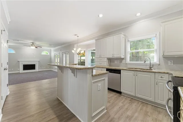 a kitchen with granite countertop a sink cabinets stainless steel appliances and a window
