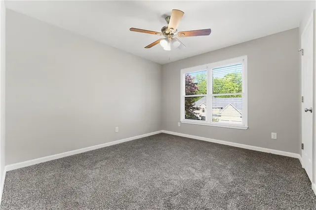 an empty room with windows and ceiling fan