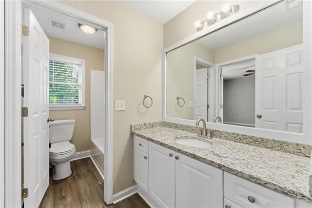 a bathroom with a granite countertop sink a toilet and a mirror