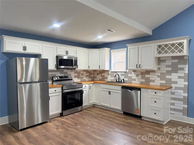 a kitchen with granite countertop a refrigerator stove a sink and dishwasher with wooden floor