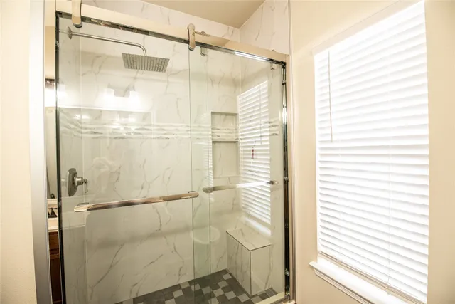a bathroom with a glass door shower and a window