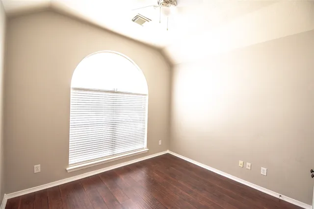 an empty room with wooden floor and window