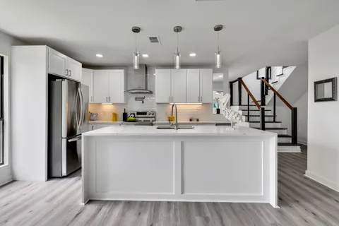 a kitchen with stainless steel appliances granite countertop a refrigerator a sink dishwasher and a stove with wooden floor