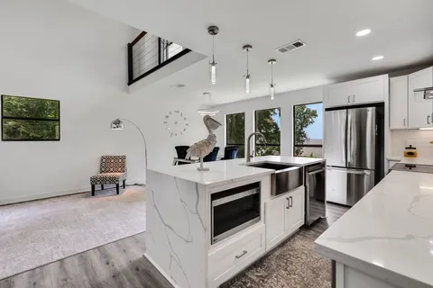 a kitchen with stainless steel appliances a white stove top oven a chimney a sink and a refrigerator