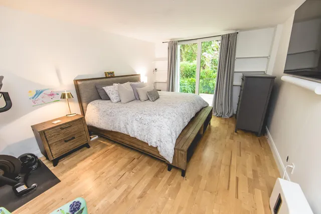 a bedroom with a bed and a flat tv screen next to a window