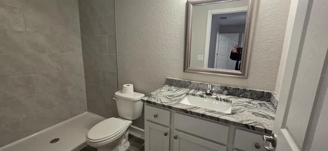 a bathroom with a granite countertop toilet a sink and a mirror