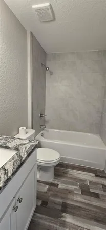 a bathroom with a granite countertop bathtub sink vanity mirror and toilet