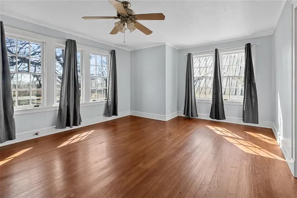a view of an empty room with a window and wooden floor