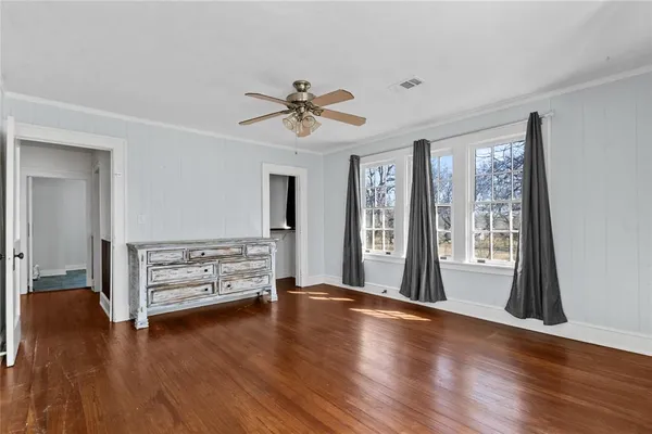 a view of an empty room with window and wooden floor