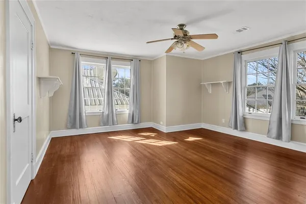 a view of an empty room with a window and wooden floor