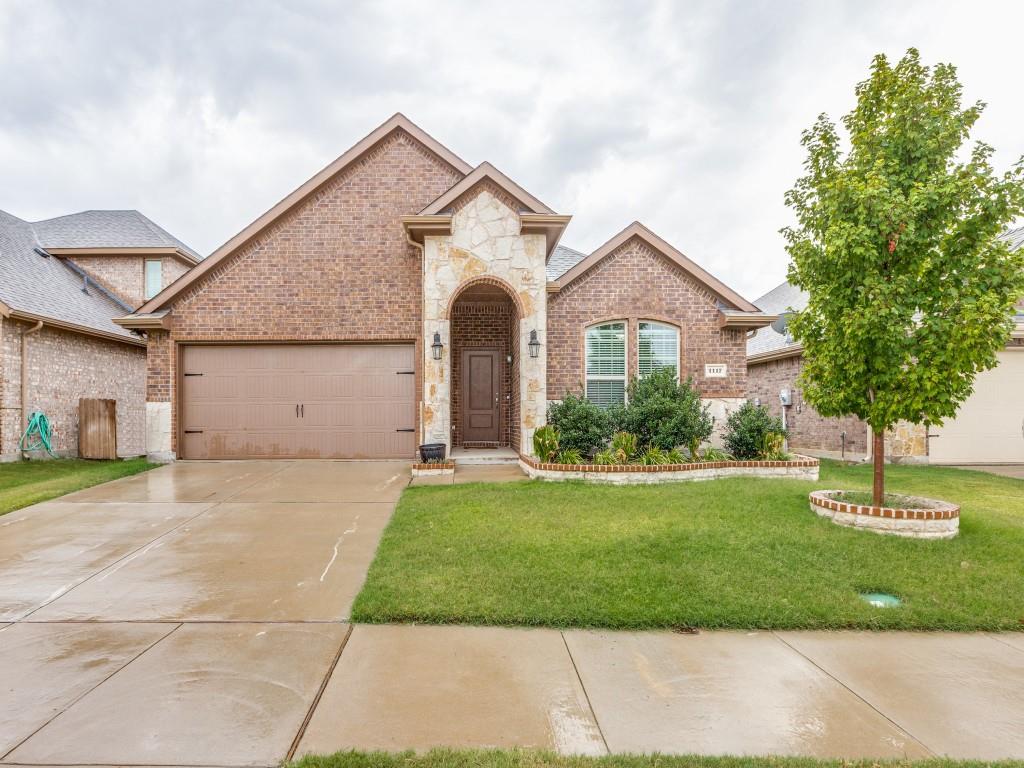 View of front facade featuring stone siding, brick siding, a front yard, and driveway