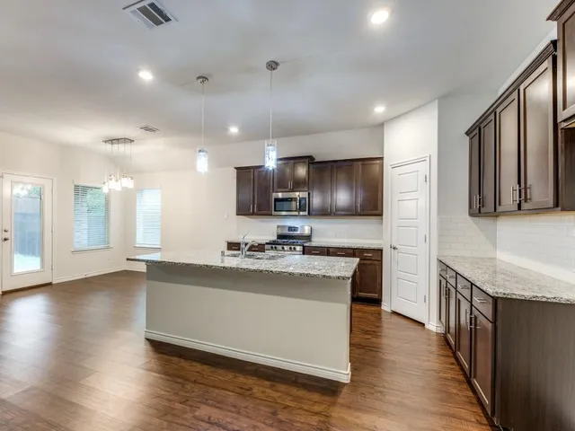 a large kitchen with stainless steel appliances granite countertop a large stove a sink dishwasher and a microwave oven with wooden floor