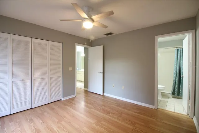an empty room with wooden floor and a ceiling fan