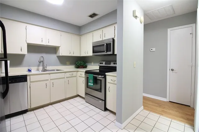 a kitchen with white cabinets a sink and appliances