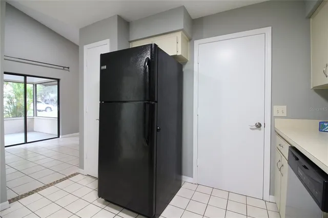 a view of a refrigerator in kitchen and an empty room in wooden floor