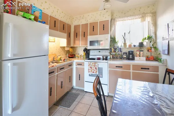 a kitchen with stainless steel appliances granite countertop a refrigerator a sink dishwasher a stove with white cabinets and wooden floor