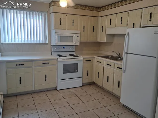a kitchen with white cabinets and white appliances