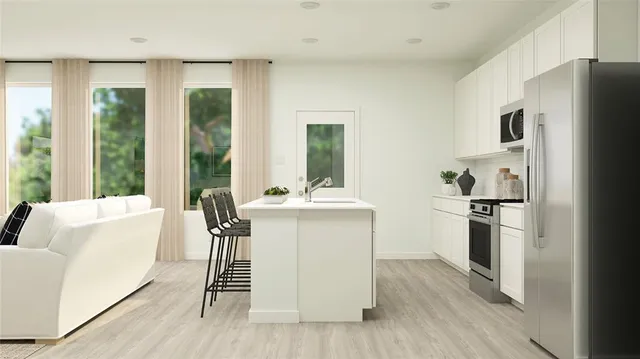 a living room with stainless steel appliances a sink a counter top space and a large window