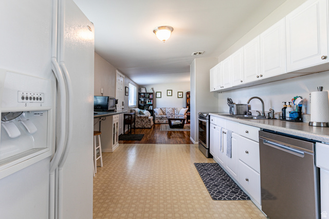 1619 Davis Drive Layton, UT 84041 - Photo 10 of 27 Kitchen featuring white cabinetry, a stainless steel dishwasher, a stainless steel sink with a gooseneck faucet, light-toned countertops.