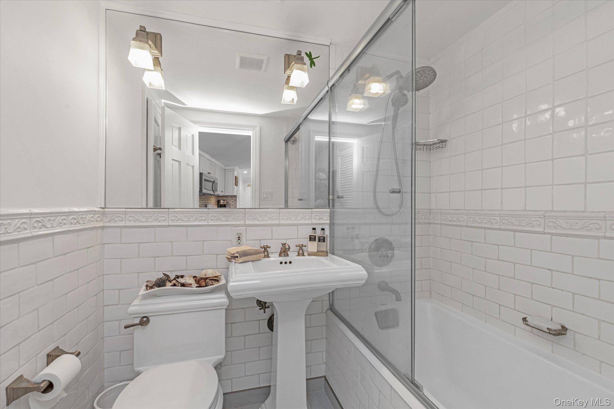 830 Shore Road, Unit 1F Long Beach, NY 11561 - Photo 11 of 21 a bathroom with a sink a toilet a mirror and shower