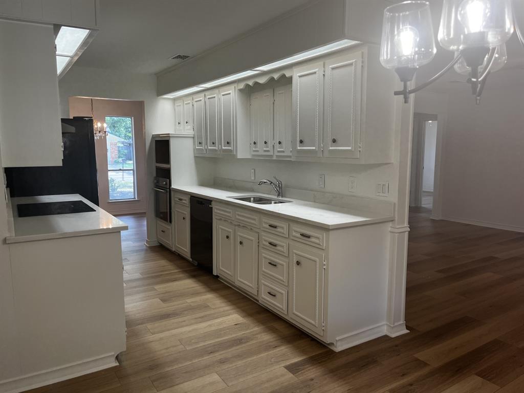 a kitchen with cabinets appliances and a wooden floor