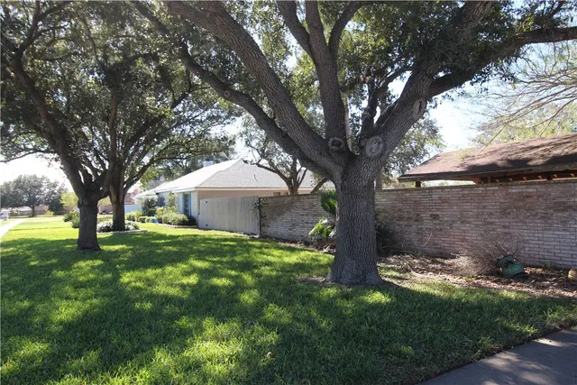 a view of a house with a yard and large trees